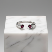 Elegant open-ended silver ring featuring twin heart-shaped ruby stones.